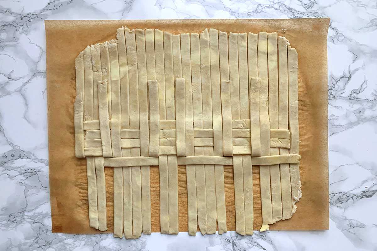 Same sheet of dough as previous image, with middle two strips in each group unfolded over horizontal strip